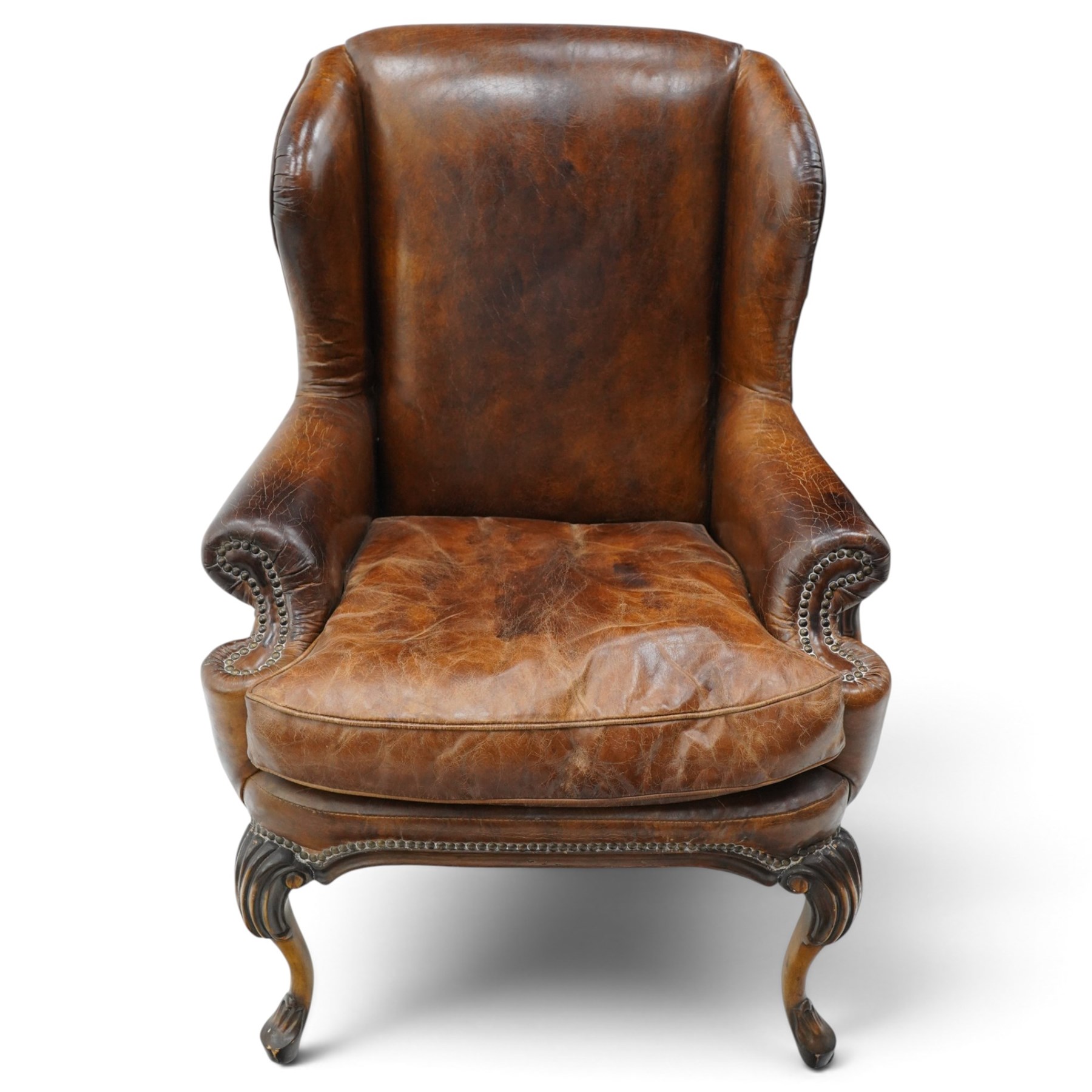 Pair of quality Queen Anne design mahogany framed wingback armchairs with matching footstools, the high sprung winged backs over rolled arms with studwork, raised on elegant reeded scroll carved cabriole supports, upholstered in deep chocolate brown leather (W82cm D75cm H112cm), the footstools with ovoid padded seat over studwork and moulded lower rail and cabriole supports (W65cm D42cm H48cm)