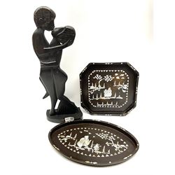 Oval wooden tray and an octagonal wooden try both with mother of pearl inlay scenes, alongside a carved wooden sculpture of a couple kissing.