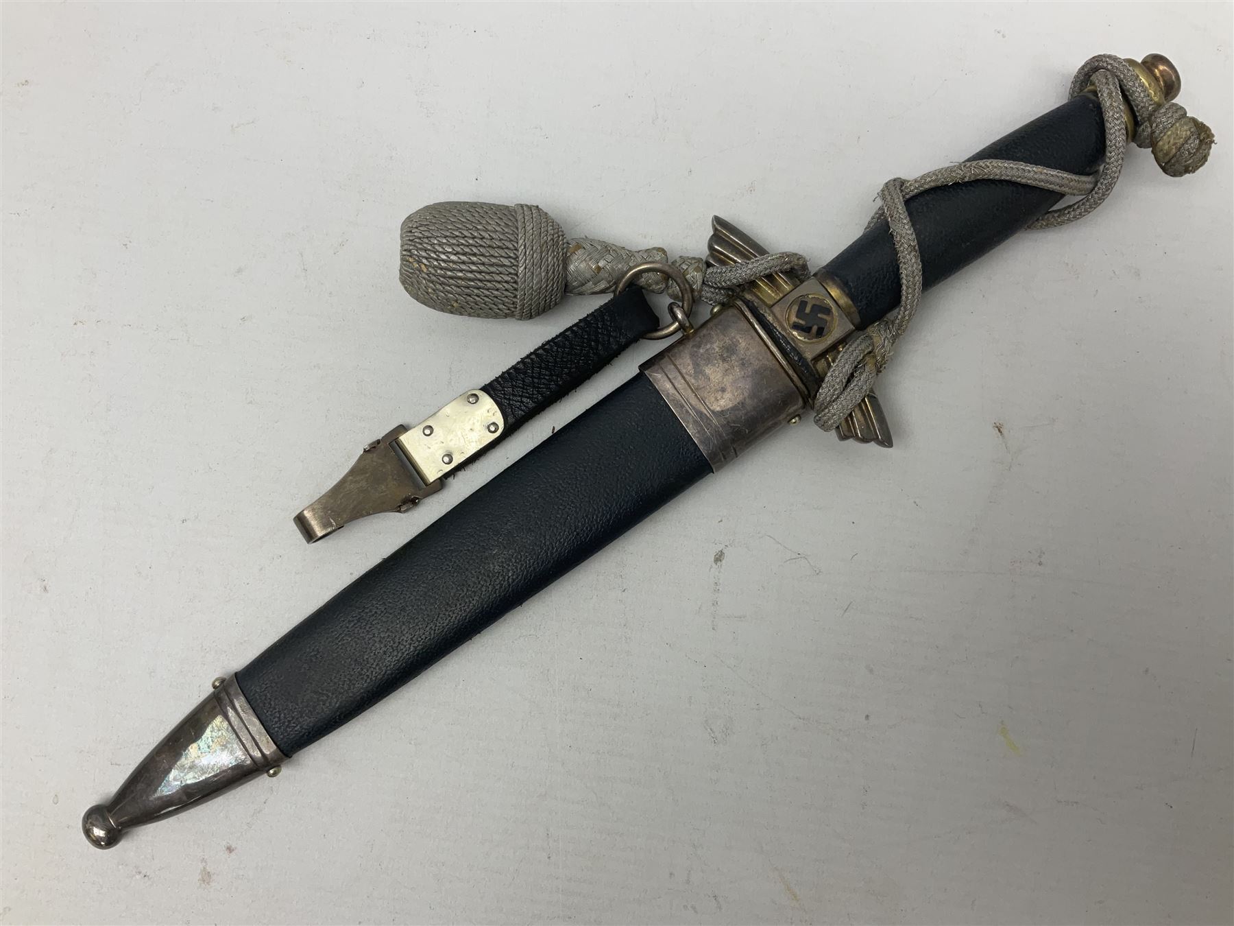 German Paul Weyersberg & Co Solingen DLV flyers dagger with 18cm steel blade, plated brass/tombac downswept cross-piece and pommel and leather covered grip, in leather and plated brass/tombac scabbard with leather hanger strap and silvered knot L35cm overall. Auctioneer's Note: After WWI Germany was forbidden an air force by the Treaty of Versailles however the Deutscher Luftsport-Verband (German Air-sport Association) was formed in March 1933 from various sports flying clubs and had branches for aeroplane, gliding and balloon flying. Under cover of the sporting DLV, many future Luftwaffe pilots trained to fly. DLV was embodied with the NSKK in March 1935 and on 1st March 1937 Luftwaffe was formed.