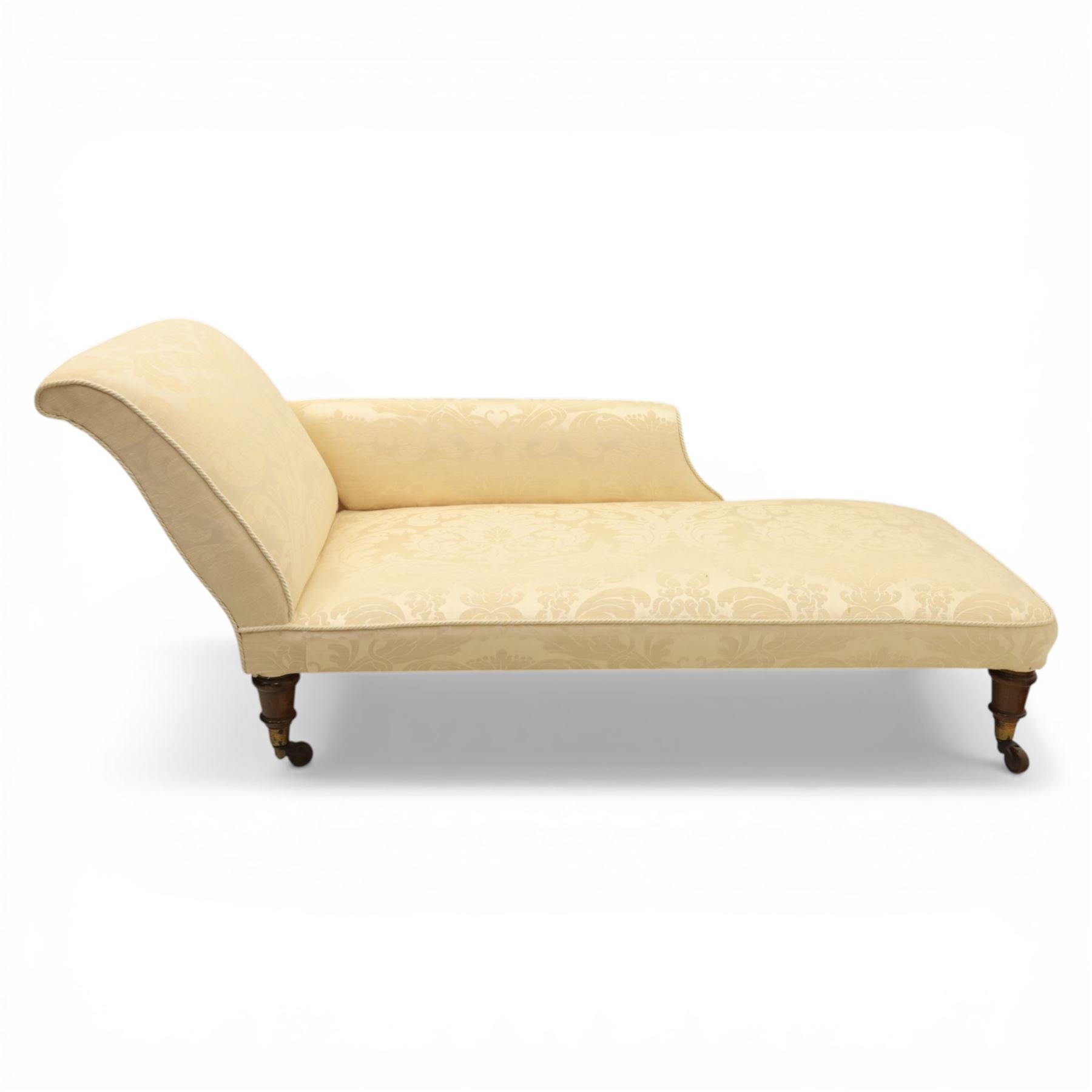 Victorian chaise longue upholstered in ivory damask fabric, padded back and armrest with rope piping, raised on turned feet with castors