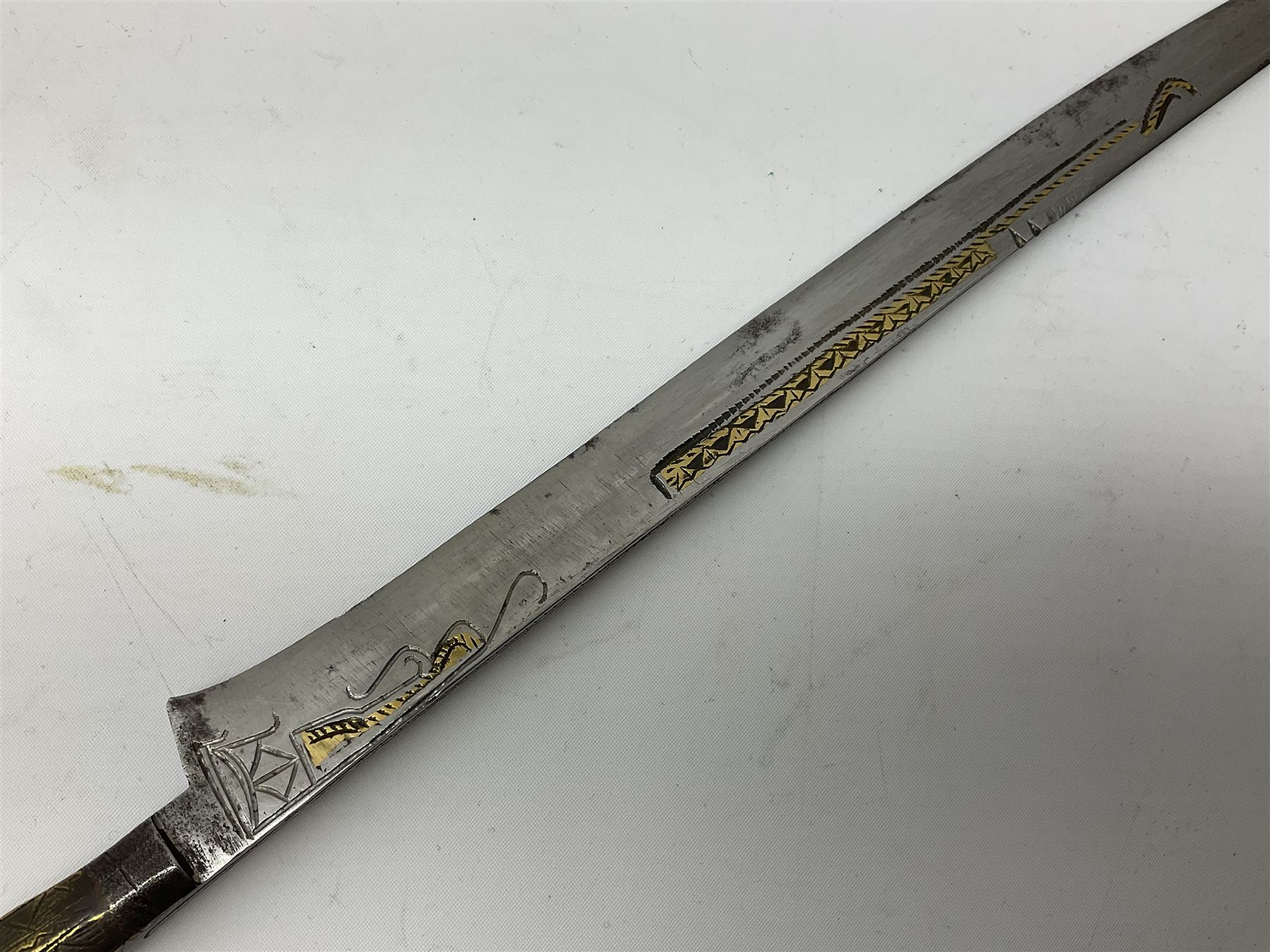 19th century Algerian Flyssa long knife, the 34cm single edged pointed decorative blade inset with yellow metal, chased brass grip with pommel as the snout of a stylised animal and carved hardwood scabbard L45cm overall