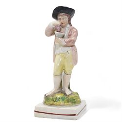 Derby porcelain model of a cherub holding a basket of flowers and wearing a chaplet, H13cm, another Derby cherub holding a basket of flowers and another Derby style cherub, together with a 19th century Staffordshire Ralph Wood type pearlware figure emblematic of Autumn, holding grapes and a goblet (4)