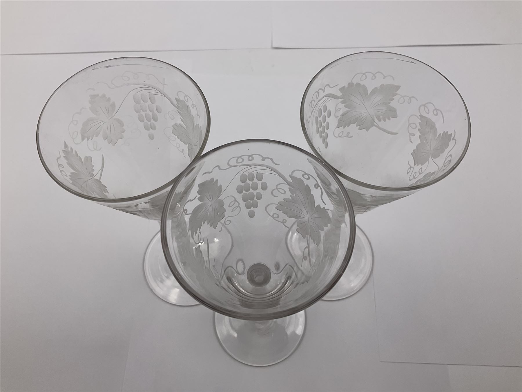 Set of three 18th century style wine glasses, each with funnel bowl etched with fruit vine, upon a double series air twist stem and circular foot, H17cm