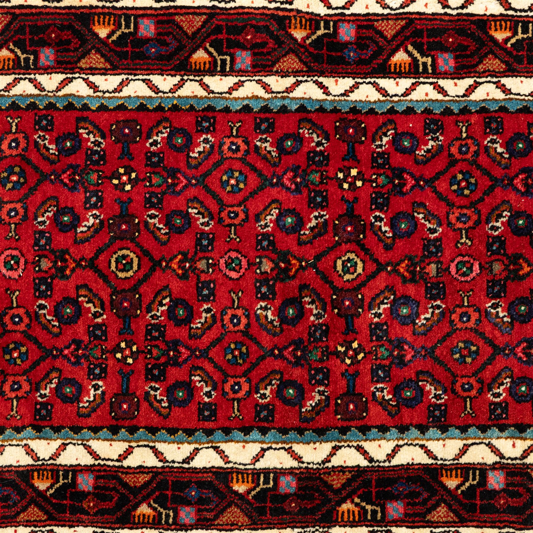 North West Persian Malayer runner, madder red field decorated with an all-over design of stylized herati motifs in shades of indigo, ivory, and green within ivory and dark blue borders of angular vine and rosette design, with cotton fringe ends 