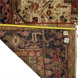 Northwestern Persian Heriz carpet, crimson ground and soft green field, with bold terracotta stepped medallion with angular spandrels and geometric motifs within a broad palmette and vine border 