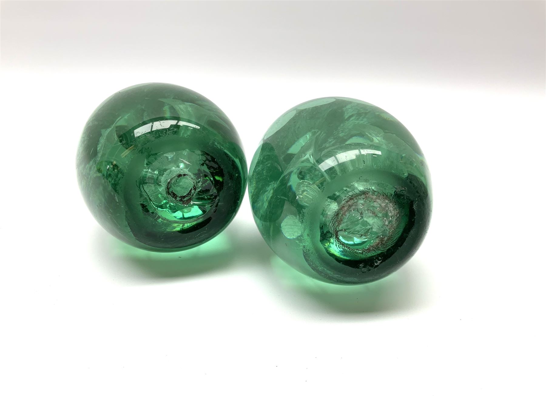 A pair of Victorian green glass dump paperweights, with internal foil