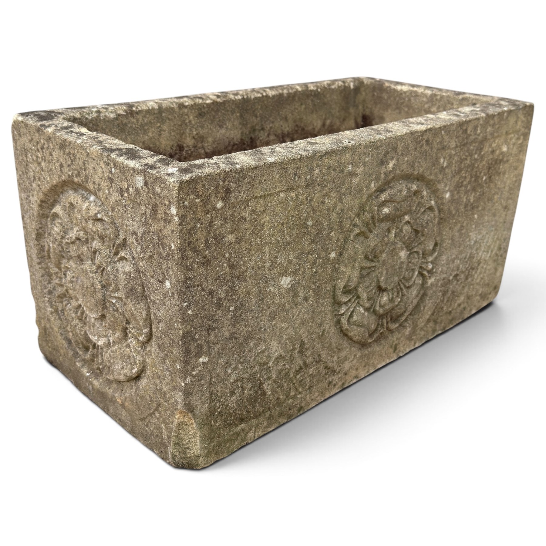 Two weathered composite stone garden trough planters, comprising a low serpentine trough relief moulded with rocaille, shell and foliate ornament (W55cm D32cm H19cm); the plain rectangular trough decorated with four moulded Yorkshire rose medallions to each side (W51cm D26cm H25cm)