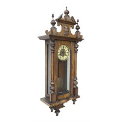 German- Late 19th century 8-day spring driven wall clock in a walnut and ebonised case, with a broken pediment and turned finials, fully glazed door with a visible pendulum and two part ivorine dial, chapter with roman numerals and minute track, rack striking movement sounding the hours and half hours on a coiled gong. With key .