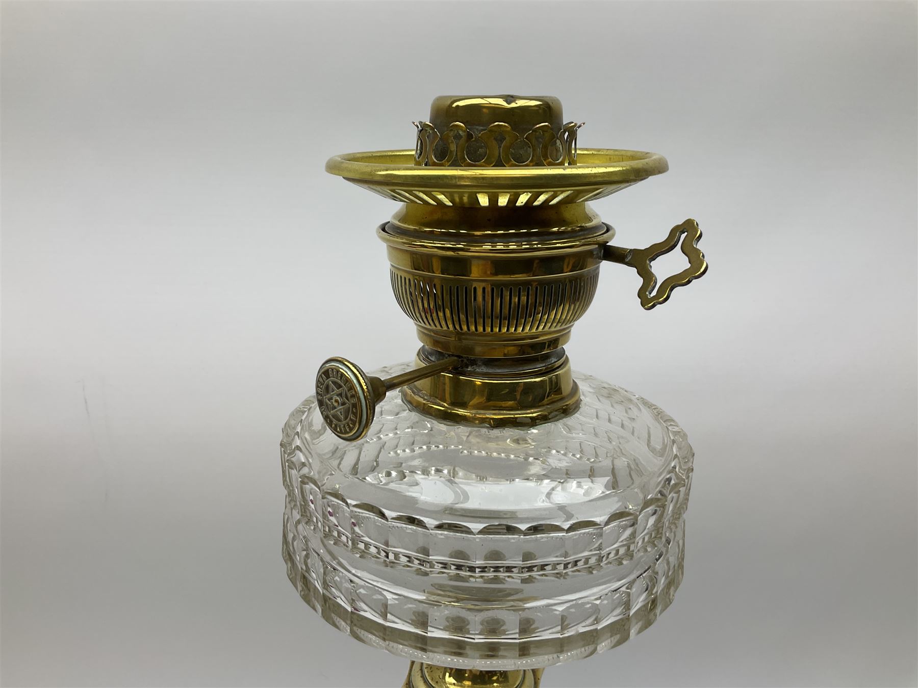 Victorian brass oil lamp, the square stepped base leading to a Corinthian column supporting a part slice cut clear glass reservoir, burner, clear glass chimney and foliate etched glass shade with amber rim, overall H80cm