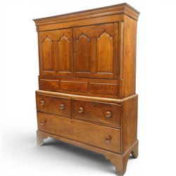 18th century oak larder cupboard, projecting moulded cornice over two panelled doors with shaped arched fielded panels, three short dummy drawers above base fitted with two short and one long drawer, turned handles, on bracket feet