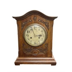 English - 20th century art nouveau period 8-day striking mantle clock in an oak case, with conforming carving and a serpentine pediment, painted steel dial with Arabic numerals, minute track and spade hands,  twin train going g barrel movement, striking the hours on a coiled gong. With pendulum and key.