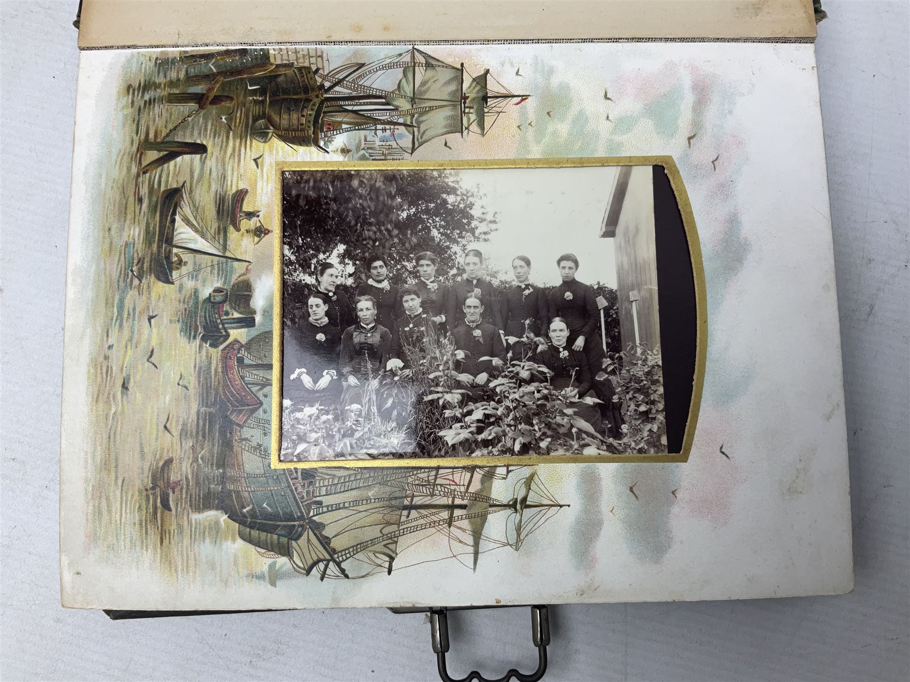 Victorian desk ink blotter, decorated with painted spray of flowers within stylised gilt rococo spandrels with mother of pearl fixings, together with a Victorian photo album containing interior leaves with apertures of various sizes and shapes of portraits surrounded by printed sea and dock scenes, blotter L28cm