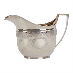 George III silver three piece tea service, comprising teapot with ivory scroll capped curved handle and ivory finial to the hinged cover, twin handled open sucrier with gilt interior, and cream jug with gilt interior, each of oval form with rounded sides, the bodies engraved with central monogram within a seaweed wreath, between engraved foliate bands, hallmarked John Emes, London 1801, teapot including handle H17cm

This item has been registered for sale under Section 10 of the APHA Ivory Act