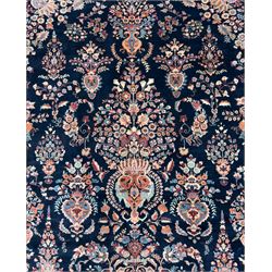 Northeastern Persian Meshed carpet, the deep navy field with a symmetrical floral arrangement of stylised flowerheads, palmettes and scrolling vines issuing from a central urn, enclosed by broad rust and blue borders of floral arabesques and lotus forms, from the region of Meshed