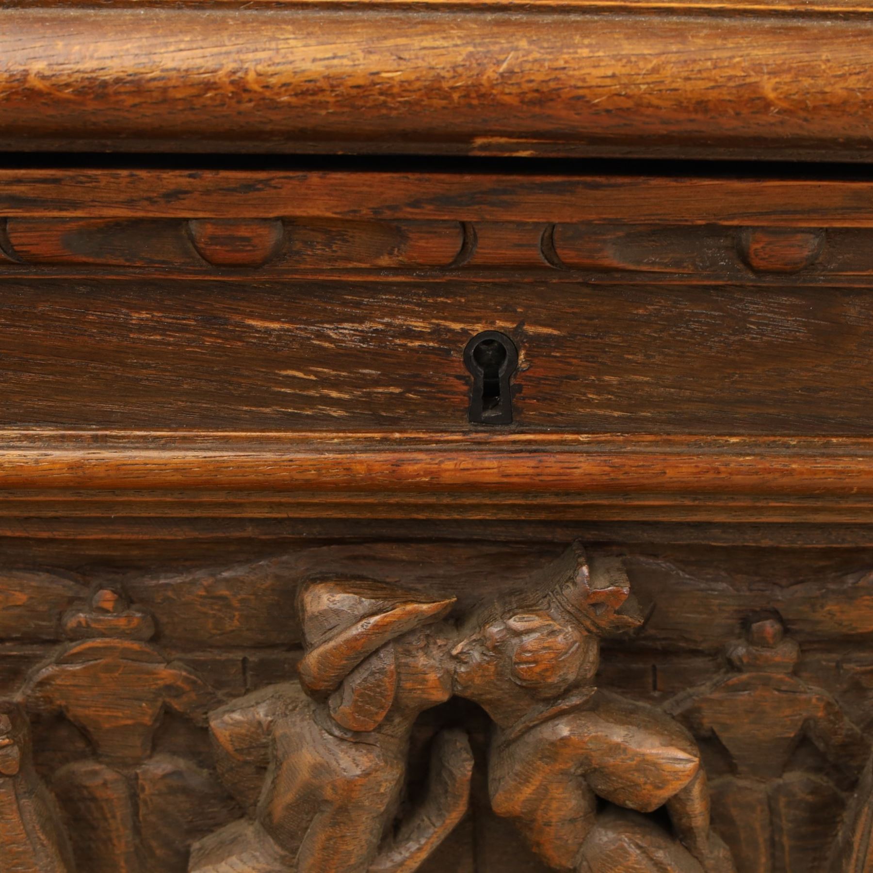 Carved oak coffer bench, rectangular moulded top above carved fall front, with figural, mask and foliate decoration, panelled sides, raised on turned bun feet with shaped lower apron