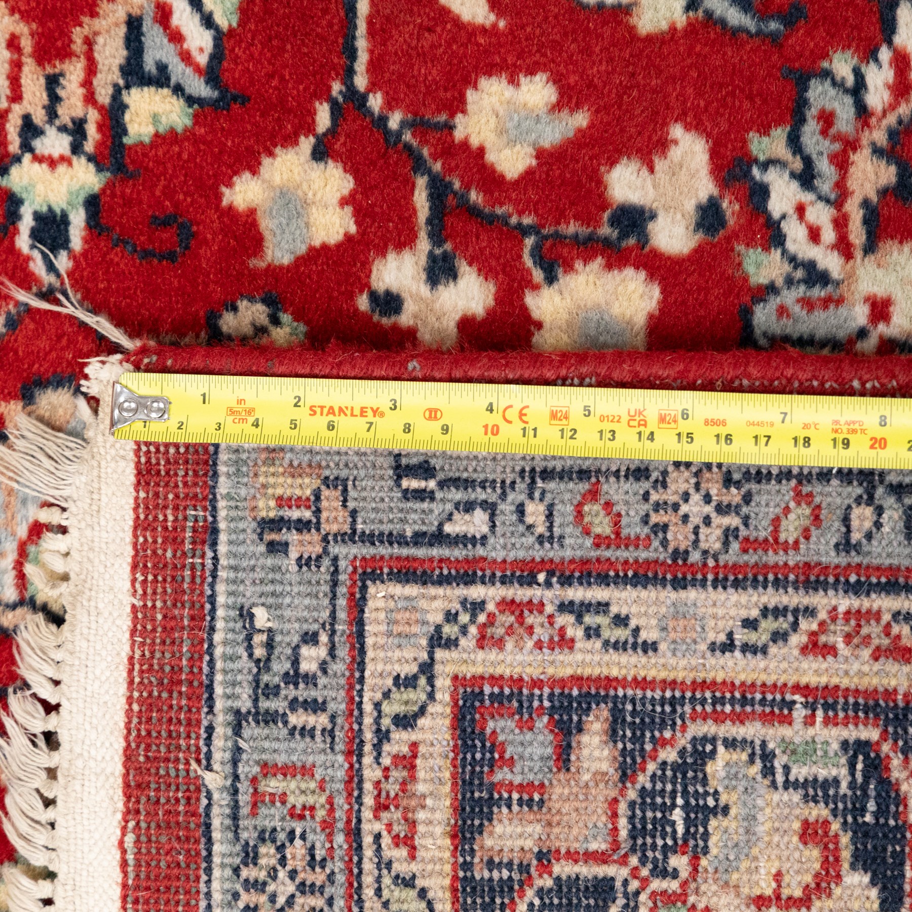 Persian crimson ground rug, interlacing floral stems linking ivory palmettes, rosettes and serrated leaves, within a navy floral border flanked by ivory patterned guards