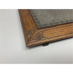 Arts and Crafts oak stand by Arthur Simpson of Kendal, of rectangular form with central hammered pewter panel, surrounded by a border with carved foliate corners, upon two bar supports, bearing label detailed 