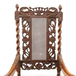 Late Victorian Jacobean Revival oak armchair, the caned back within a pierced and carved foliate frame surmounted by acorn finials, carved scroll arm supports, caned seat, on barley twist supports united by stretchers and carved front rail