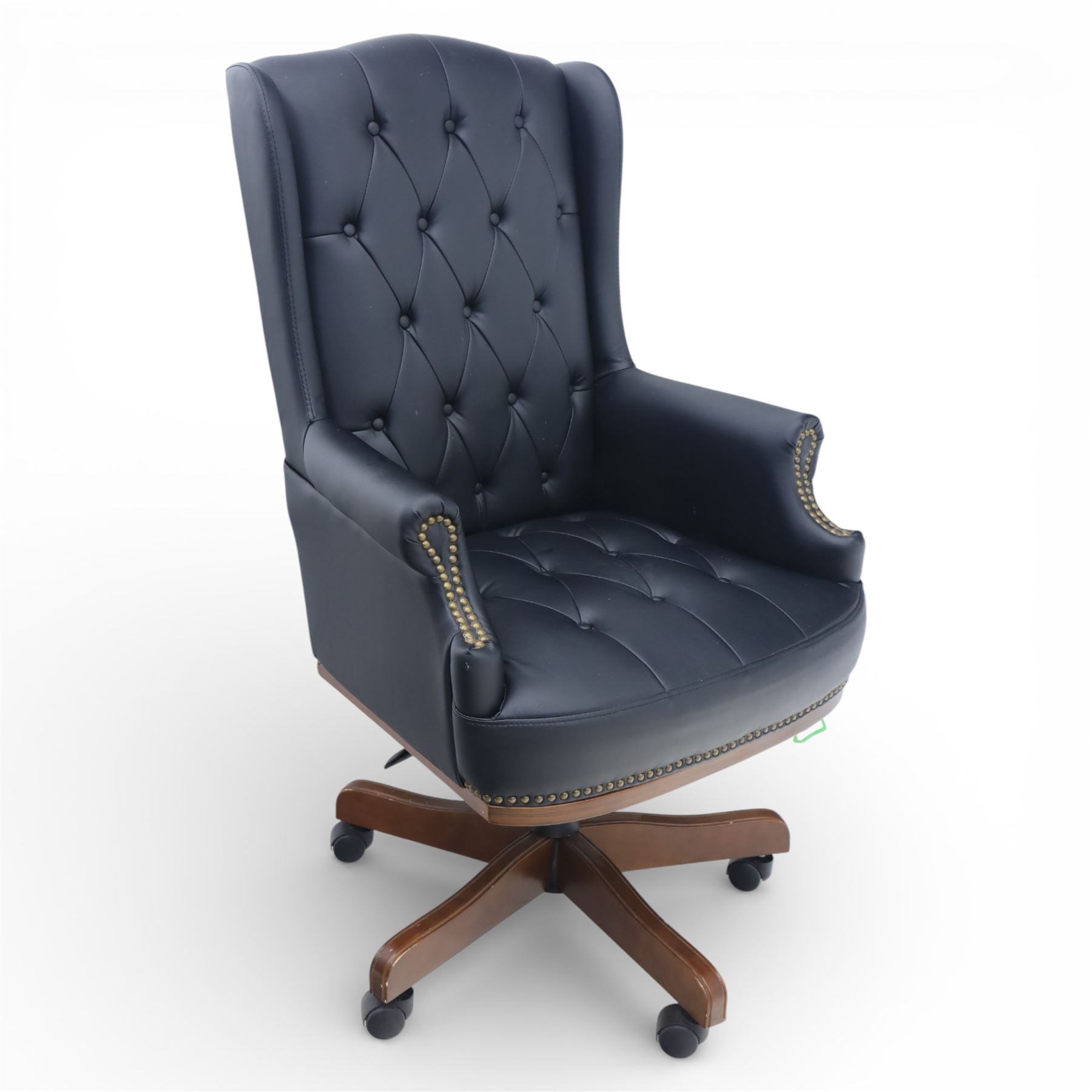 Chesterfield style desk chair upholstered in black, brass studded trim with tall button backed seat, with faux wooden base raised upon castors