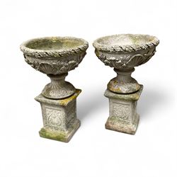 Pair of cast stone ornate garden urns, on plinth bases