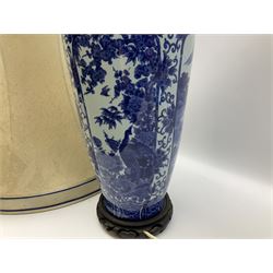 A Chinese blue and white table lamp, of slender baluster form decorated with alternate panels of landscapes and phoenix amongst blossoming peony and prunus trees, with fabric shade, lamp base H46.5cm.