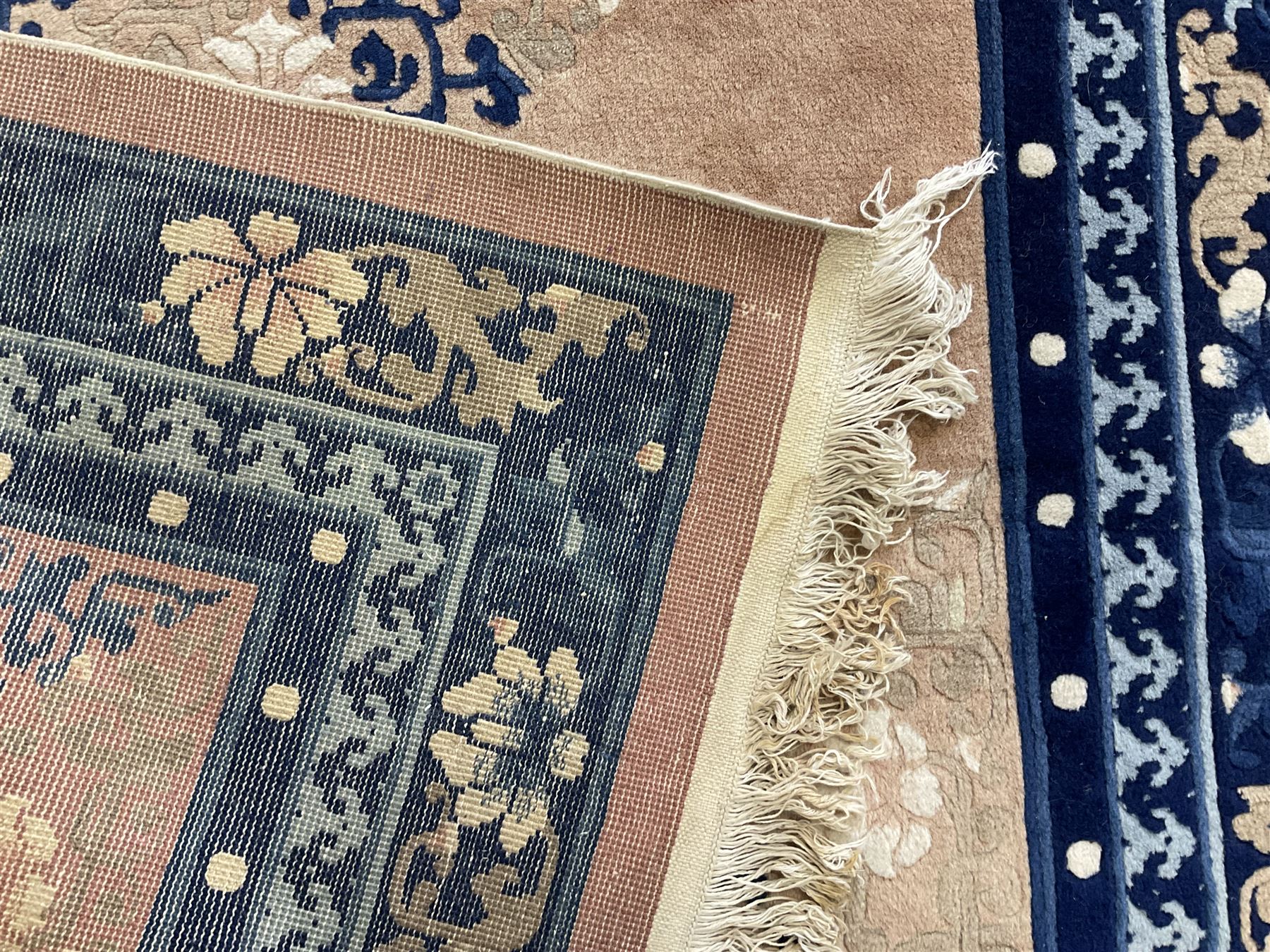 Chinese washed woollen peach ground rug, indigo borders and trailing foliate decoration, central medallion decorated with flowerheads 
