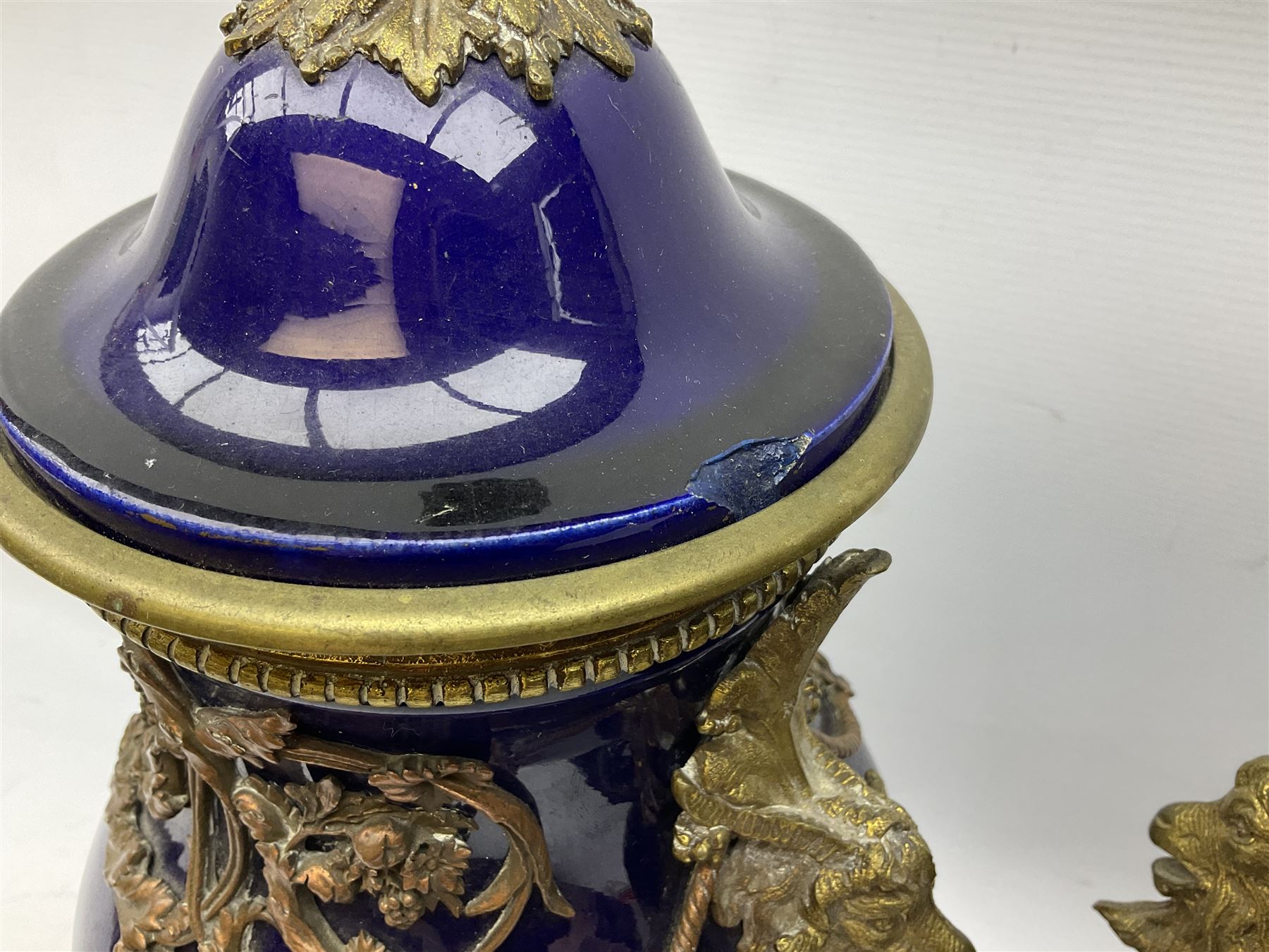 Pair of French large cobalt blue lidded urns, probably 19th century, the body decorated with ormolu ram's heads and ornate foliate design, the domed cover with brass berry finial, raised upon pedestal base with beaded decoration upon shaped plinth, H52cm