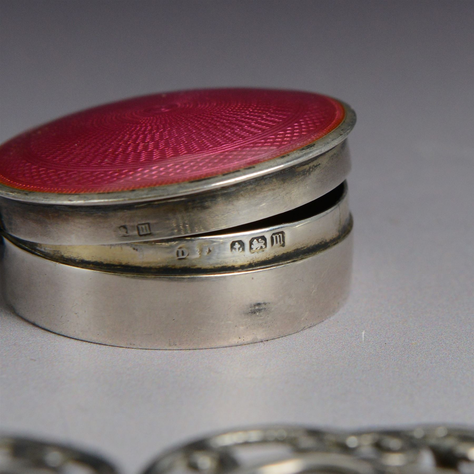 Early 20th century silver pill box, of circular form with pink guilloche enamel lid, hallmarked Deakin & Francis, Deakin & Francis Ltd, Birmingham 1911, together with a commemorative Queen Victoria belt buckle, and a pair of late Victorian dwarf candlesticks with weighted bases, all hallmarked, box D4cm