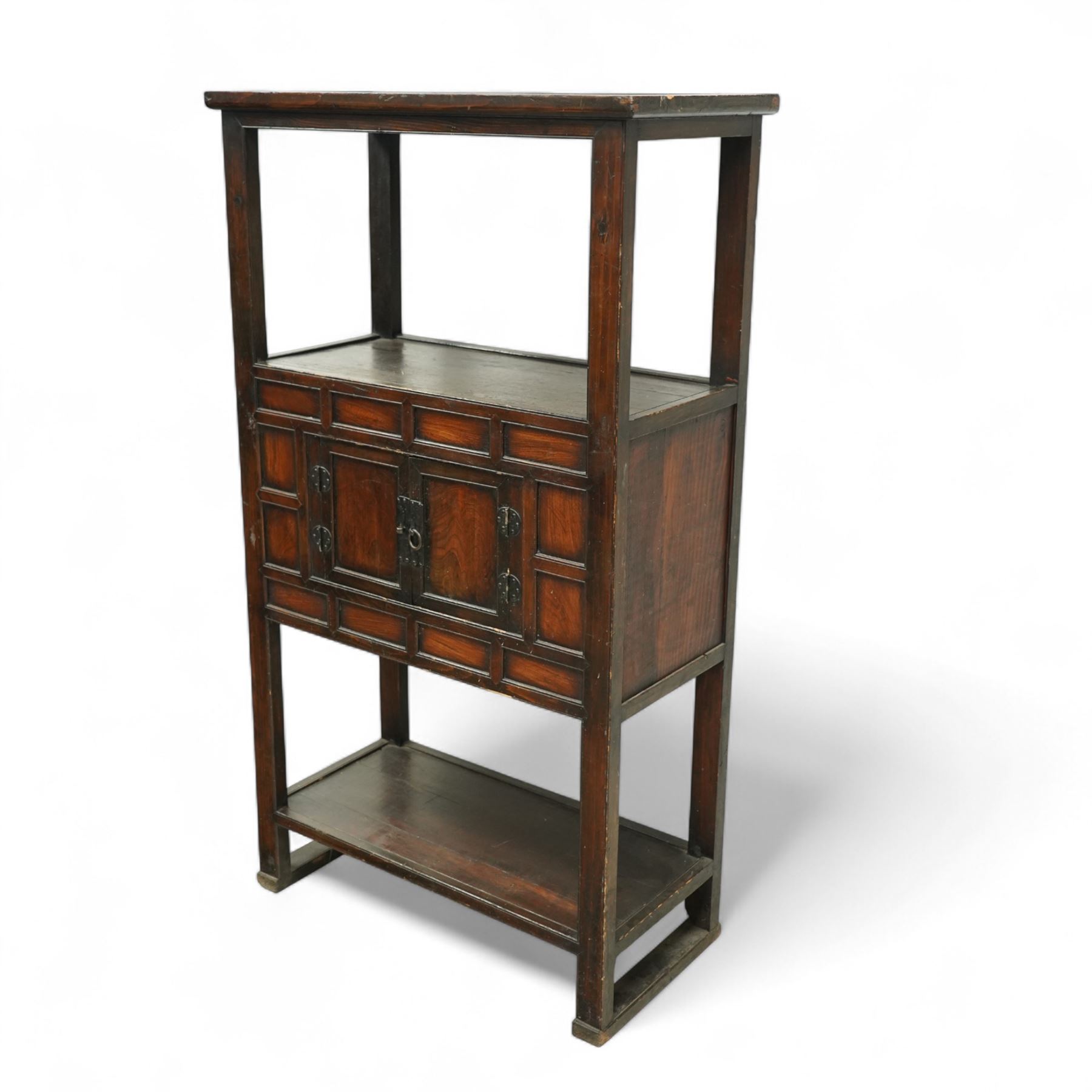 20th century Korean stained pine and elm cabinet, rectangular top over central panelled cupboard doors with metal ring handles, framed by geometric mouldings, open shelf above and below