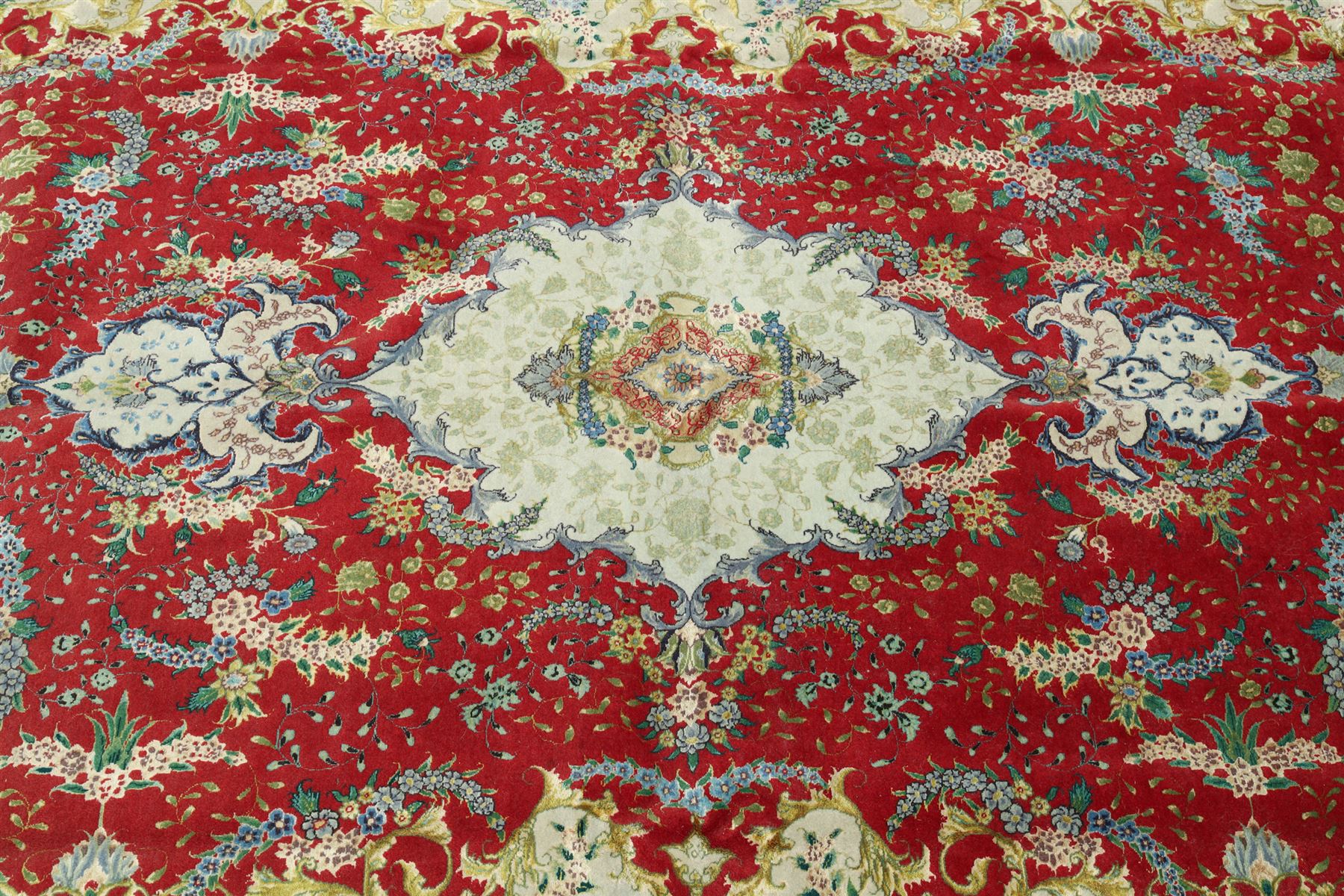 Persian silk inlaid crimson ground Kashan rug, the central shaped field with a floral pole medallion surrounded by trailing floral motifs and festoons of flowerheads, the wide cyan guard line with repeating palmettes and scrolling floral vines