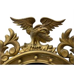 Pair of Regency period giltwood convex wall mirrors, moulded circular frame decorated with spherical mounts surmounted by a carved eagle with spread wings, foliage scroll carved upper and lower brackets, reed moulded and ebonised slip enclosed convex mirror plate 