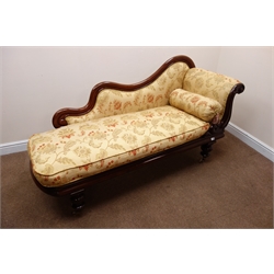  Early Victorian mahogany framed scrolled end chaise longue, shaped back, upholstered in antique gold and floral fabric, turned supports on cupped brass castors, L180cm  