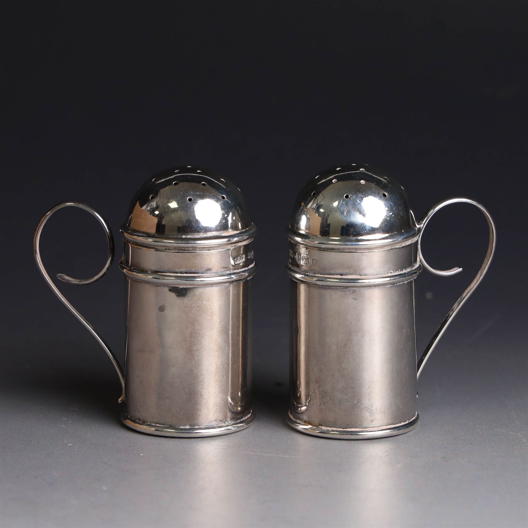 Pair of Edwardian silver muffineers, of cylindrical form with C scroll handles and removable pierced covers, hallmarked G E Walton & Co Ltd, Birmingham 1906, H6cm