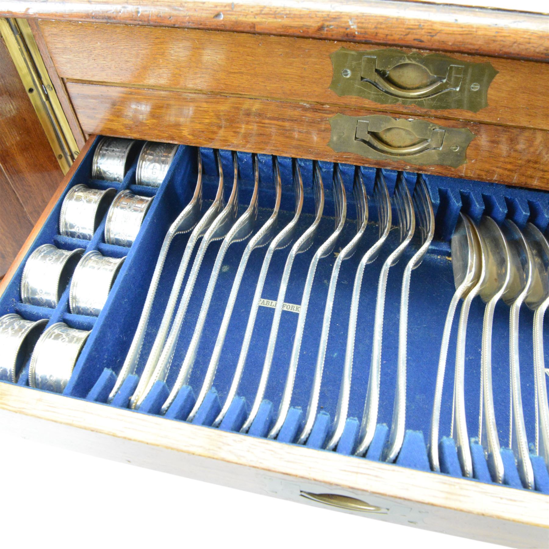 Oak table top canteen cabinet, the top with inset vacant brass cartouche, with pair of panelled doors opening to reveal four interior drawers with inset brass handle, containing a selection of silver plated flatware, 29cm x 40cm x 51cm