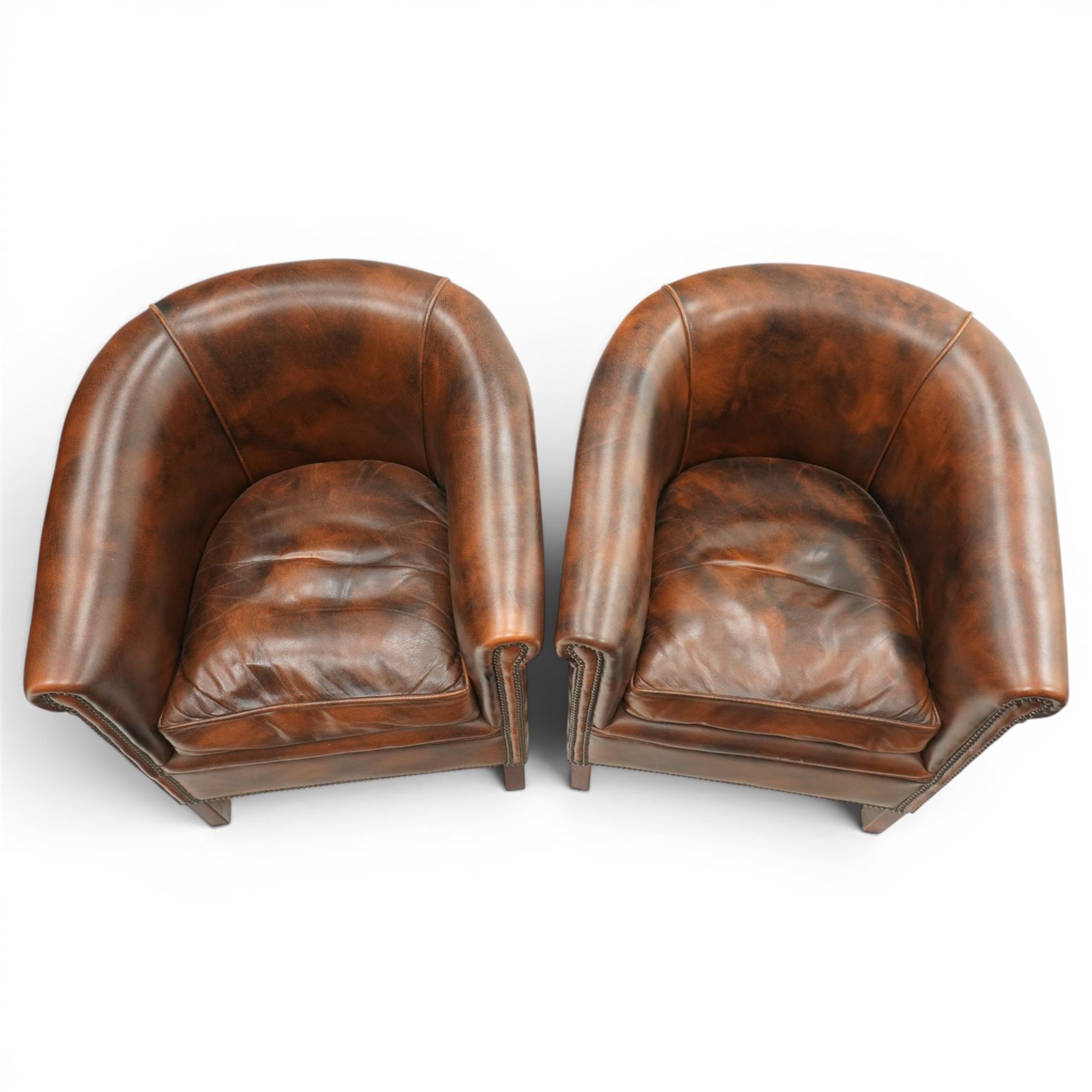 Pair of brown leather tub chairs, with downswept arms with brass studded trim, fixed cushion seat, raised on square tapering supports 