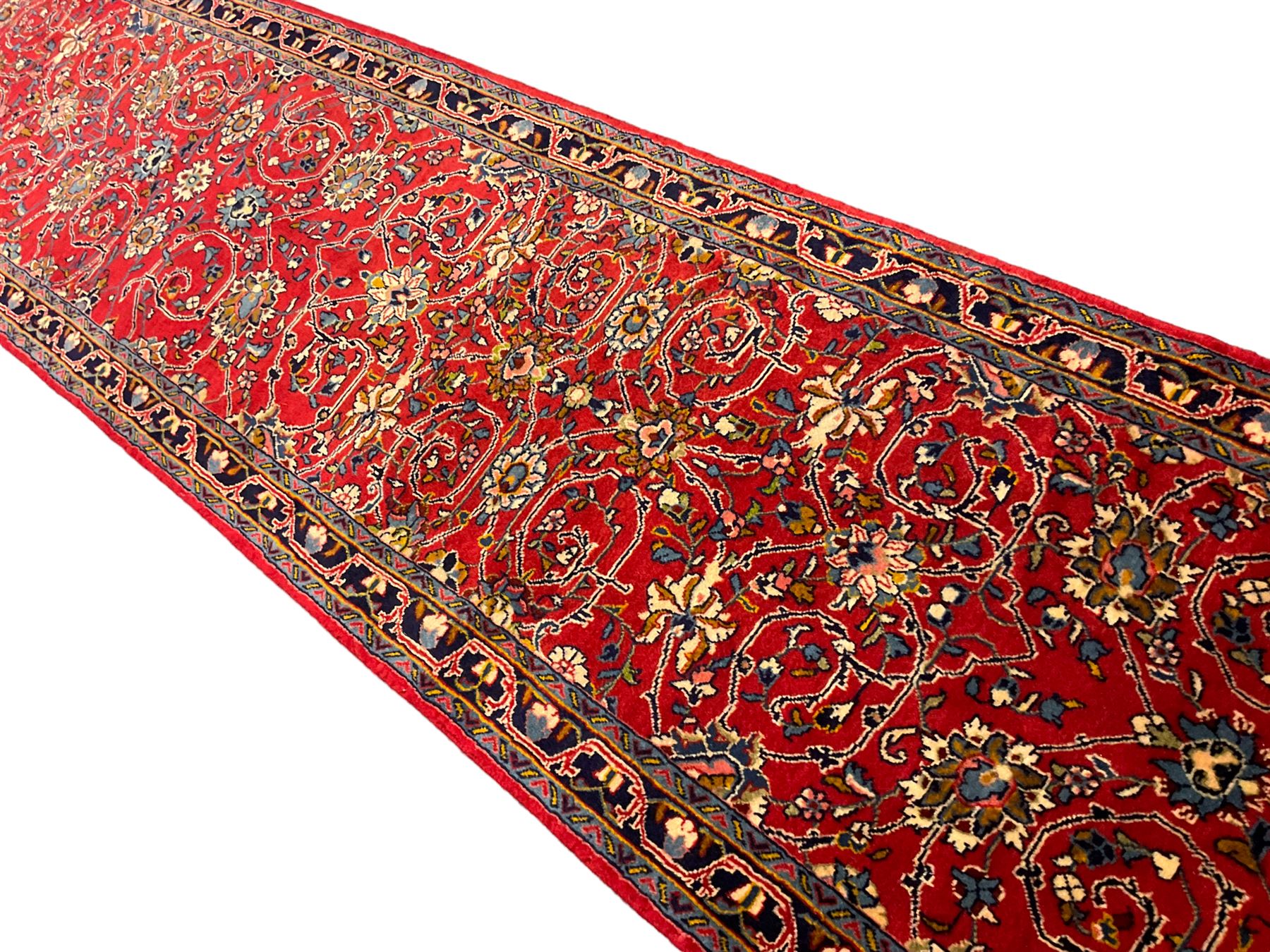 Central Persian Kashan crimson ground runner rug, the field decorated with interlacing branch and stylised flower head motifs, the guarded indigo border with repeating trailing foliate patterns