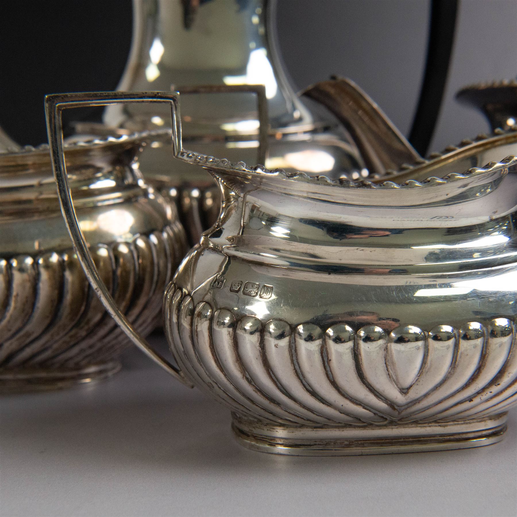 Edwardian silver four piece tea service, comprising coffee pot, teapot, twin handled open sucrier and milk jug, all of oval bellied form, part fluted and with oblique gadrooned rim, with Bakelite type handles and finials to teapot and coffee pot, hallmarked Fordham & Faulkner, Sheffield 1913