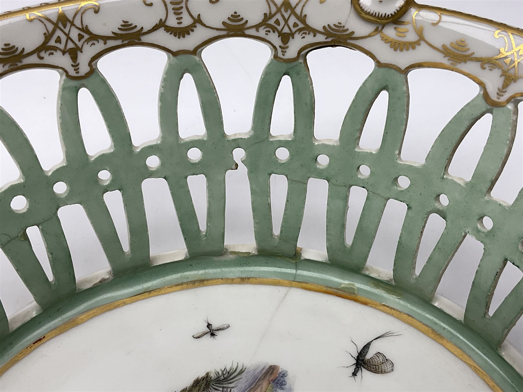Pair of 19th century German openwork chestnut baskets, with twin handles and scrolling gilt border and star rim, painted to the centre with birds and insects, D22cm 