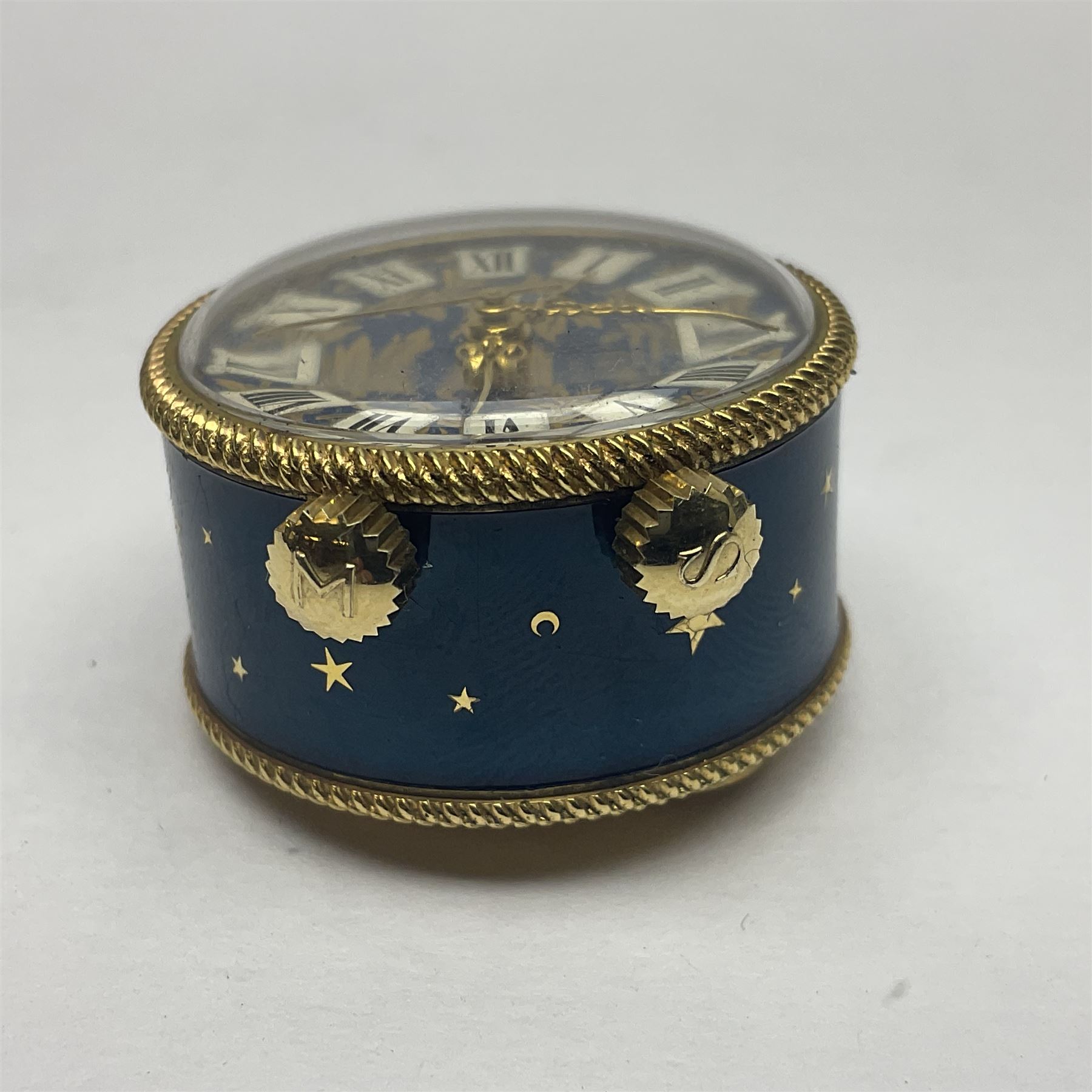Bueche Girod silver-gilt and enamel novelty miniature clock, with a band of gilt moon and star decoration upon a deep blue enamel ground, with enamel and gilt foliate dial, with musical mechanism playing happy birthday, D2.7cm, in suede pouch