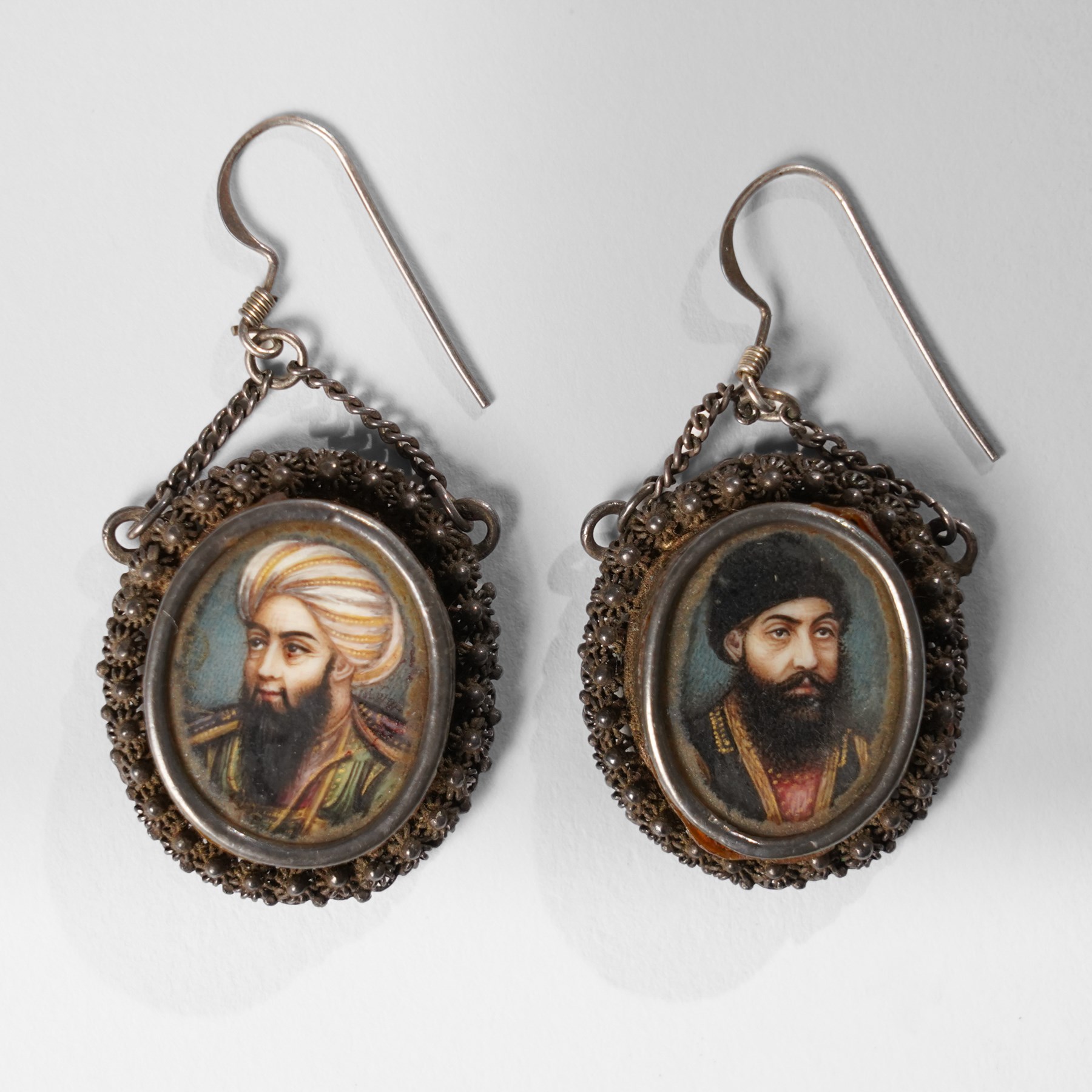 Northern Indian/Company School (19th Century): Emir Dost Mohammad Khan and his son Sher Ali Khan, pair of portrait miniature earrings on ivory, mounted in silver with filigree borders, likely commissioned during the period of British diplomatic engagement in Afghanistan (c.1860-1880), inscribed verso, each miniature approx. H2cm This item has been registered for sale under Section 10 of the APHA Ivory Act