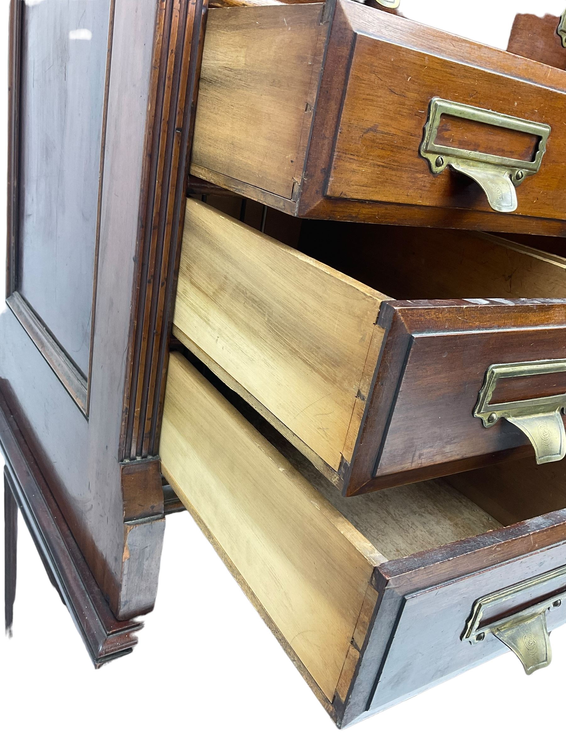 The Shannon Limited - late Victorian walnut filing cabinet, fitted with twenty-four small filing drawers, each with brass handle with label holder, fluted uprights, double cupboard below enclosed by two panelled doors, on turned feet, with brass plaque inscribed 'The Shannon, Limited, Ropemaker St. London, E.C.'