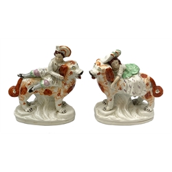 Pair of Victorian Staffordshire figures, modelled as two children, probably Queen Victoria's children, seated upon the backs of two large dogs, each upon an oval base, tallest H22cm