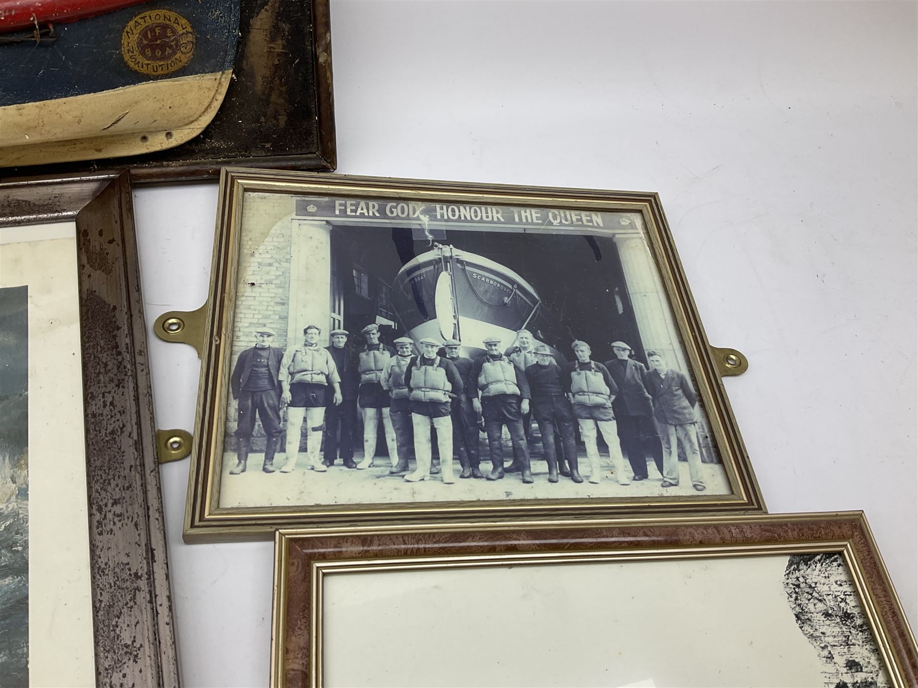 RNLI collection box in the form of a boat makers half block model, painted in the colours of a lifeboat with flag and ship motifs, H25cm, L73cm together with framed photos, postcards and prints of lifeboats and crew, including Scarborough lifeboat station