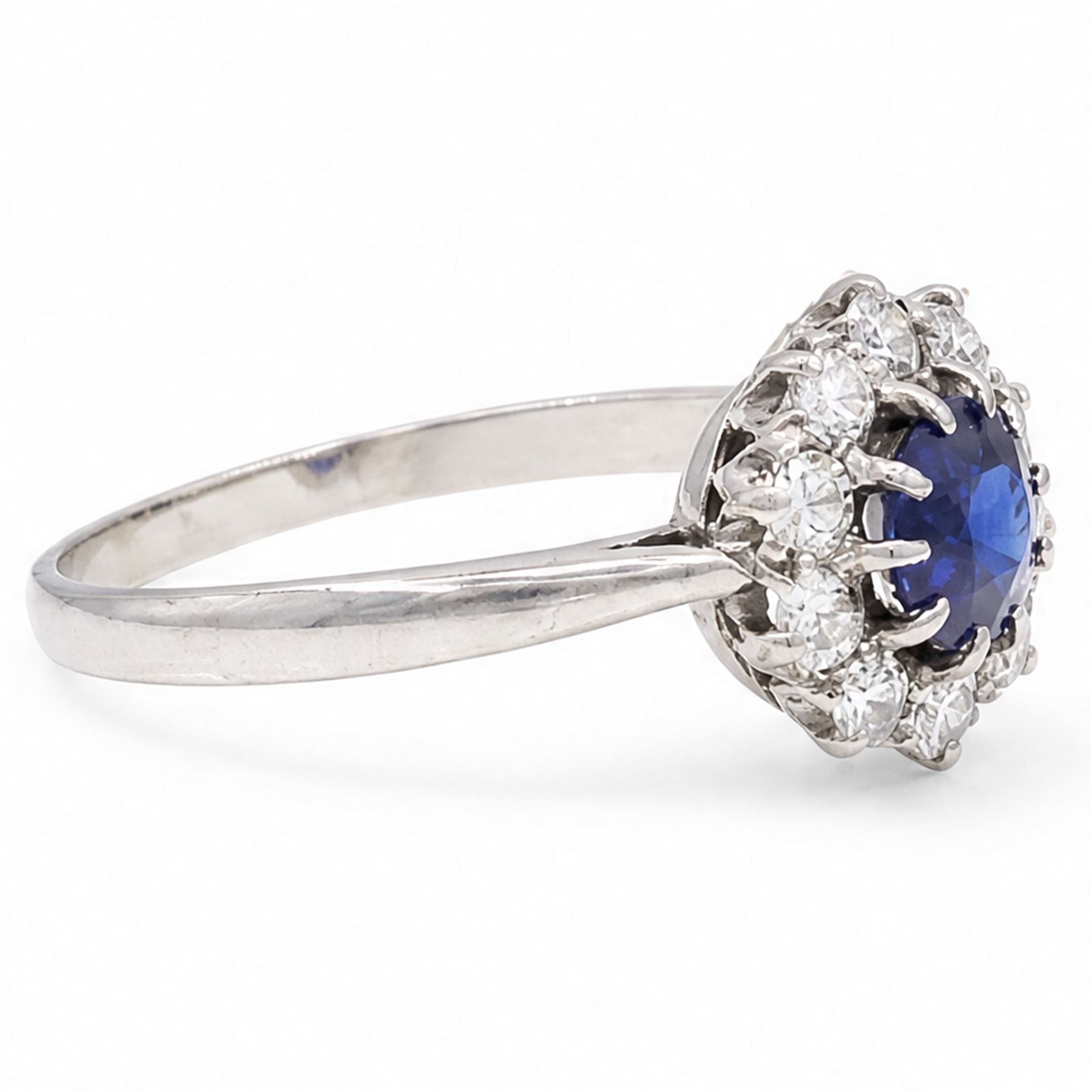 Platinum sapphire and diamond cluster ring, single round cut sapphire of approx 0.85 carat, surrounded by ten round cut diamonds, total diamond weight approx 0.40 carat