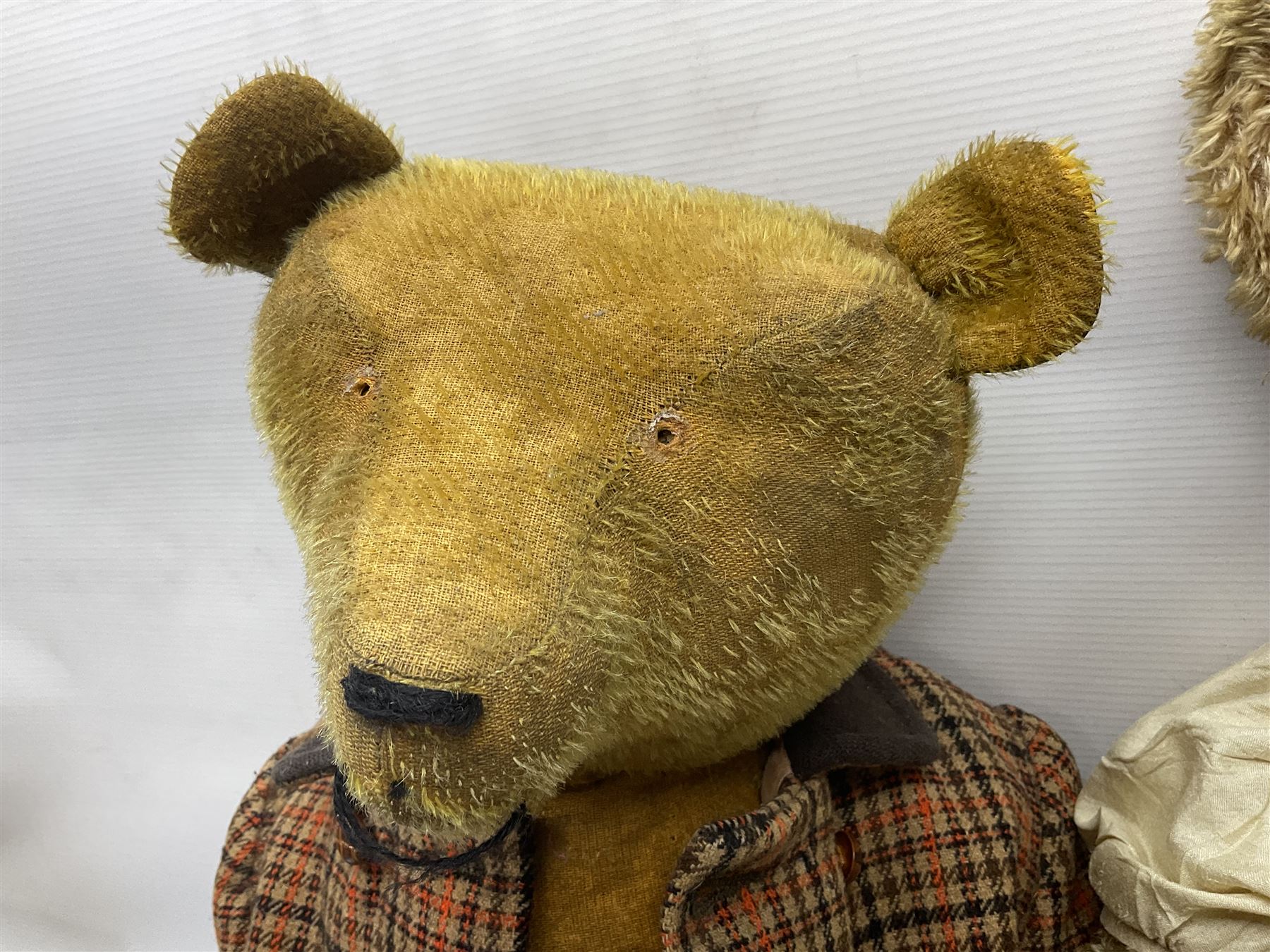 Two early 20th century straw filled jointed teddy bears, first example wearing a tweed jacket bearing Geoffrey Saville label, with leather padded paws and ears, horizontally stitched nose and humpback; second example with applied eyes, vertically stitched nose and faux leather paw pads, both with growler mechanisms, tallest H74cm 