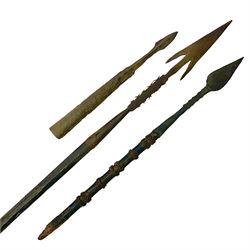Native hand forged iron fishing spear, the V-shaped head with barbed neck and hewn haft L171cm; and two other hand forged iron spear heads, one with remains of copper bound haft (3)