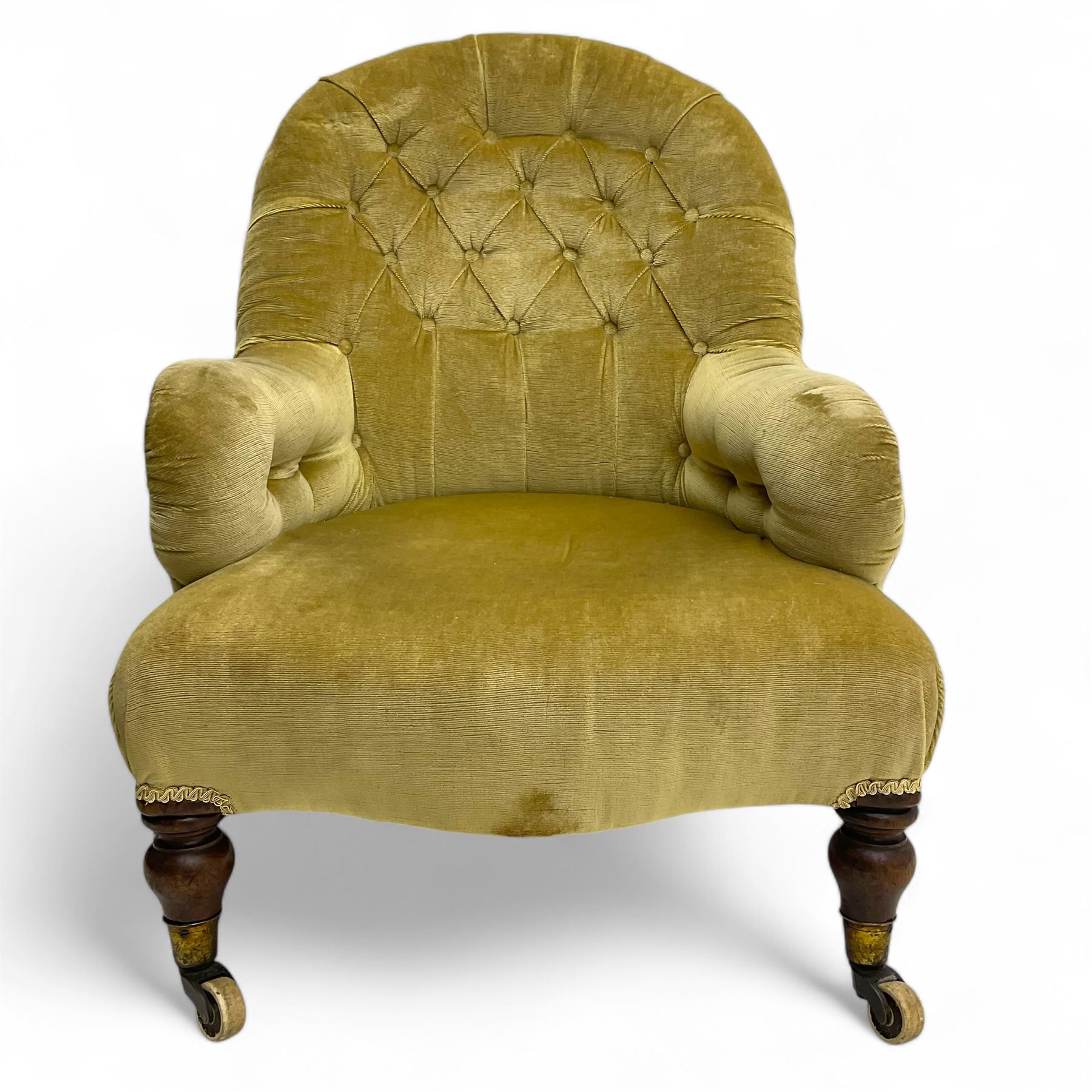 Late 19th century button-back nursing chair, upholstered in olive-green velvet, shaped back with padded arms, raised on turned front supports terminating in castors