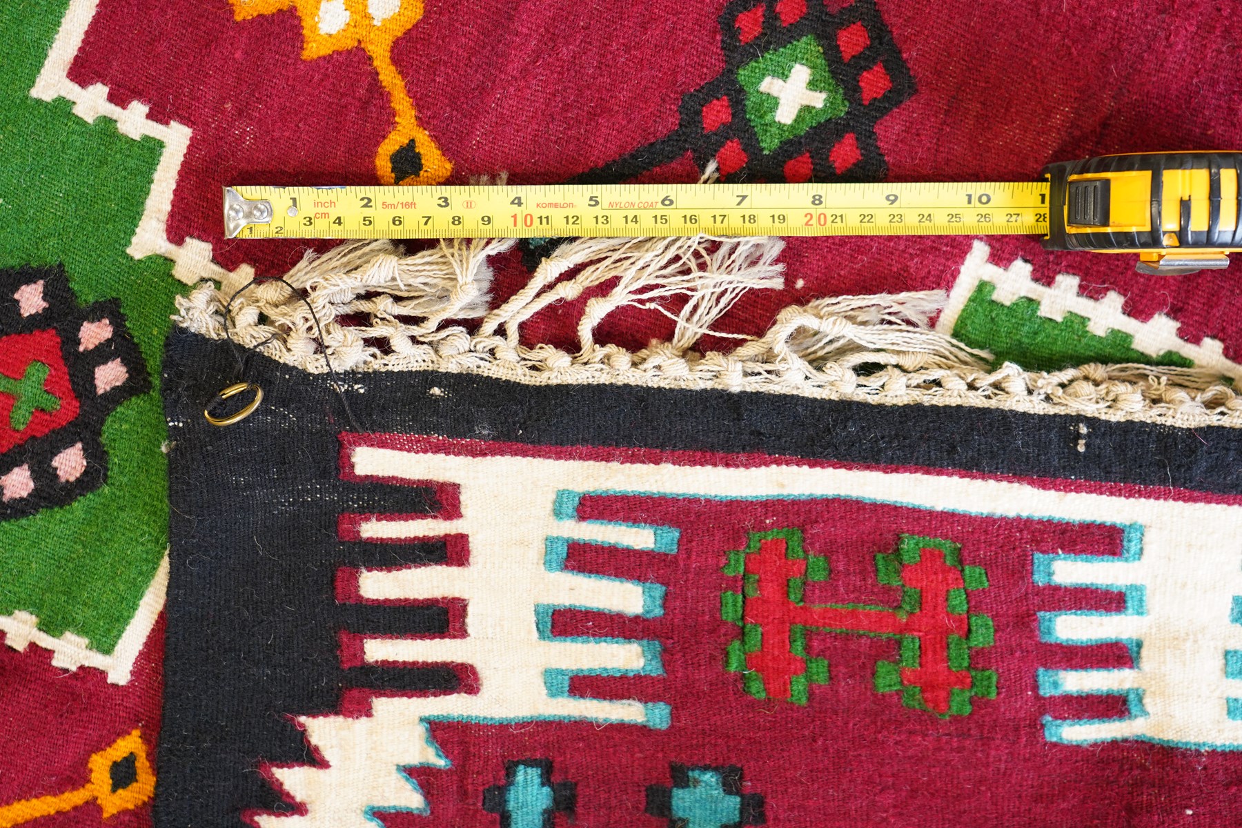 Persian Fars province crimson ground kilim rug, decorated with two rows of geometric emerald green motifs containing stylised plant designs, enclosed by an ivory and dark indigo guard band