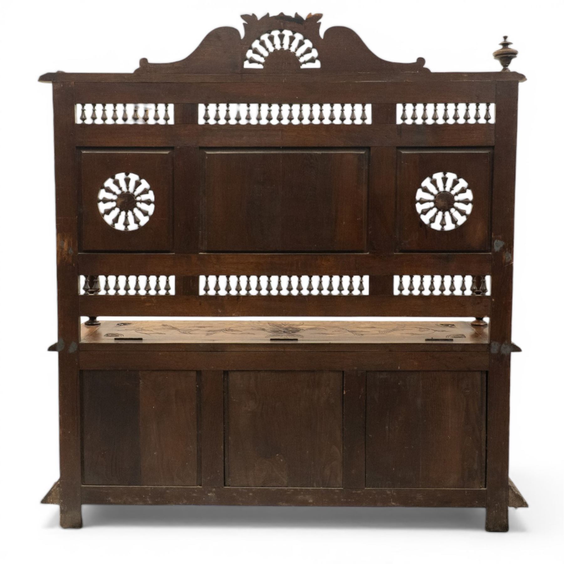 19th century European heavily carved oak hall settle, the impressive high-back with a pierced and carved acanthus pediment, over foliate and rosette carved back rails, flanking a central panel depicting a gentleman on horseback drinking, the hinged box seat over a quadruple panelled front with relief carved busts, lower moulded and carved edge on compressed bun feet