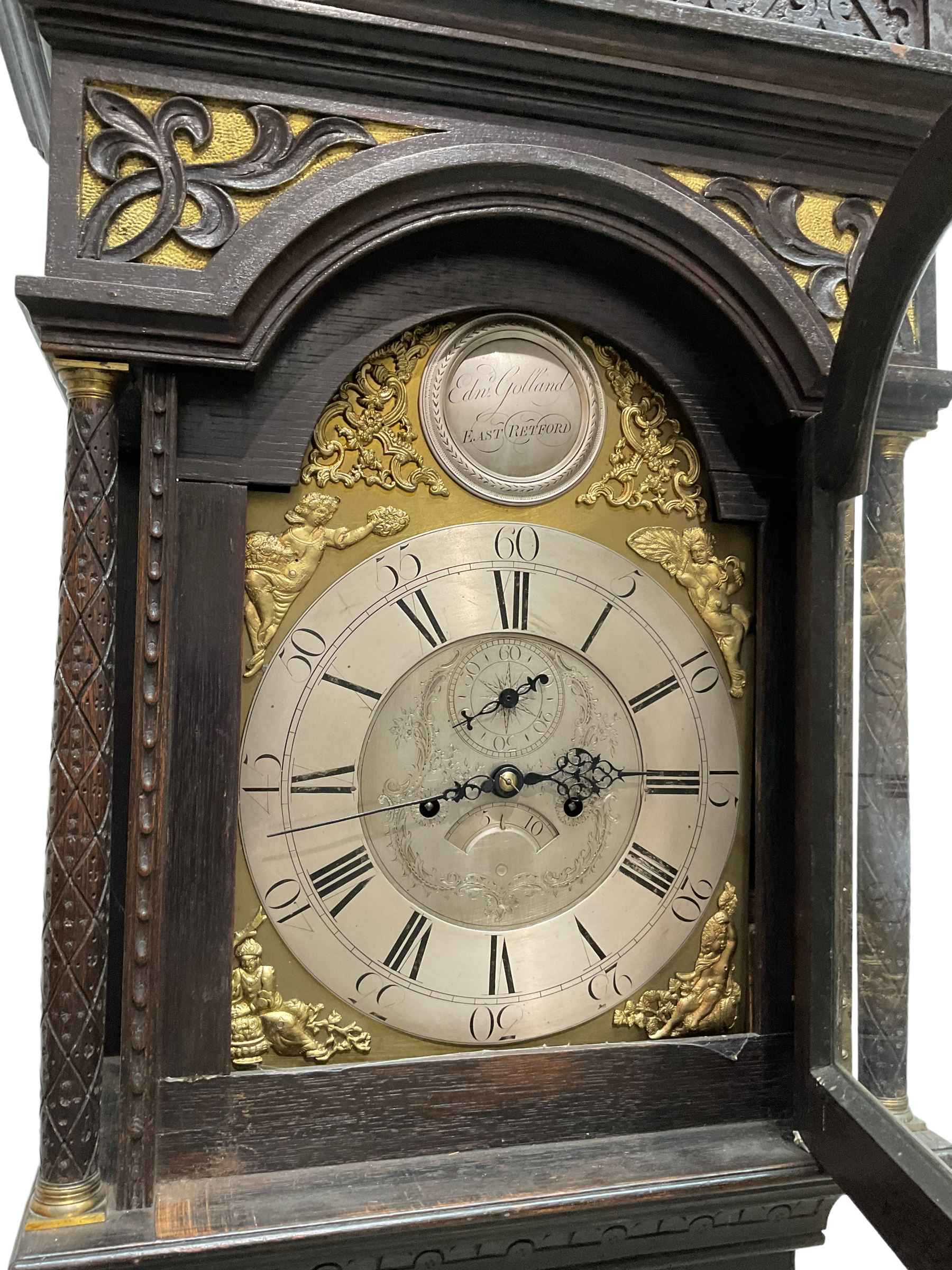 Edward Golland of Retford (Notts) - mid-18th century 8-day carved oak longcase c1760 , with a stepped caddy top and blind fret, break arch hood door flanked by carved pilasters with brass capitals,  trunk with a carved break arch toped door on a carved plinth with applied skirting and feet, brass dial with matching steel hands, silvered and engraved dial centre and chapter ring, with seconds dial and calendar aperture, four seasons spandrels and boss to the arch with makers name, four pillar rack striking movement, striking the hours on a bell. With weights and pendulum.            
Edward Golland is recorded as working in Retford during the late 18th century.